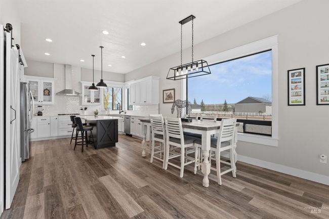 Dining space featuring a barn door, dark wood-style flooring, and recessed lighting | Image 14
