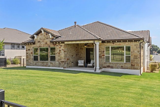 Rear view of house with stone siding, a tile roof, and ceiling fan | Image 38