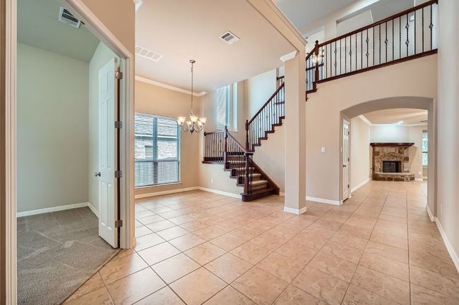 Foyer entrance featuring a fireplace, arched walkways, a chandelier, crown molding, and light tile patterned floors | Image 5