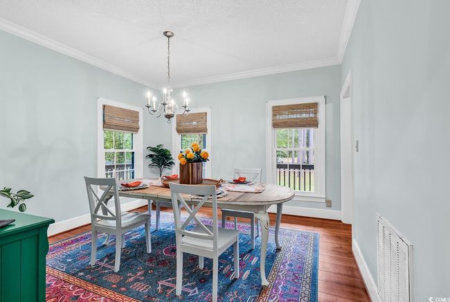 Dining area with plenty of natural light, a chandelier, wood finished floors, crown molding, and a textured ceiling | Image 8