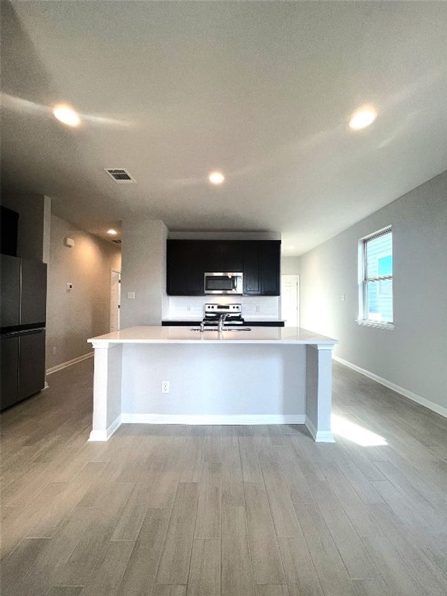 Kitchen featuring appliances with stainless steel finishes, dark cabinets, light wood-style flooring, recessed lighting, and light countertops | Image 11