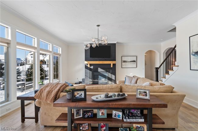 Living room featuring ornamental molding, light wood-type flooring, an inviting chandelier, and a large fireplace | Image 8