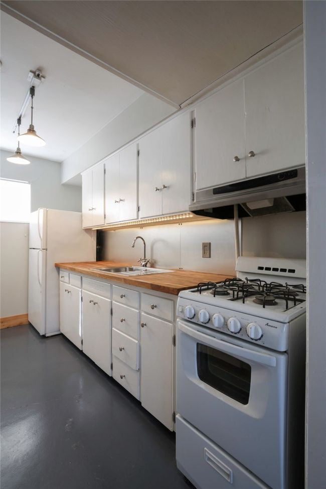 Kitchen featuring white appliances, under cabinet range hood, finished concrete flooring, and white cabinetry | Image 9