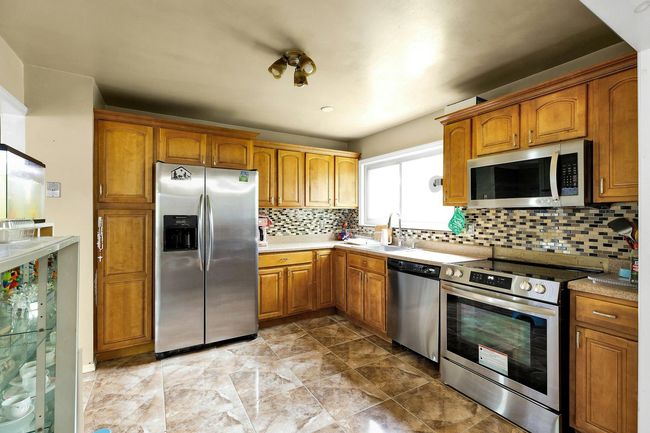 Kitchen featuring appliances with stainless steel finishes, a sink, brown cabinets, and light countertops | Image 4