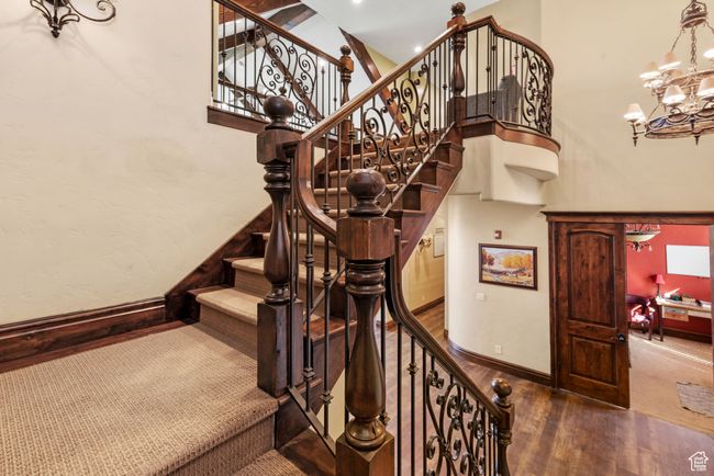 Stairway with a high ceiling, wood finished floors, a notable chandelier, and baseboards | Image 43