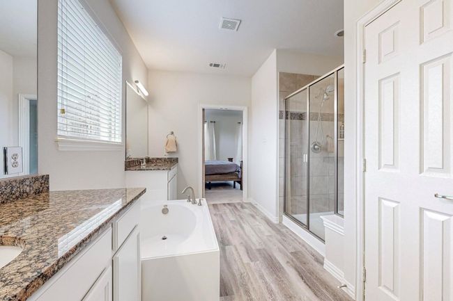 Bathroom with a stall shower, wood finished floors, ensuite bathroom, a garden tub, and two vanities | Image 32