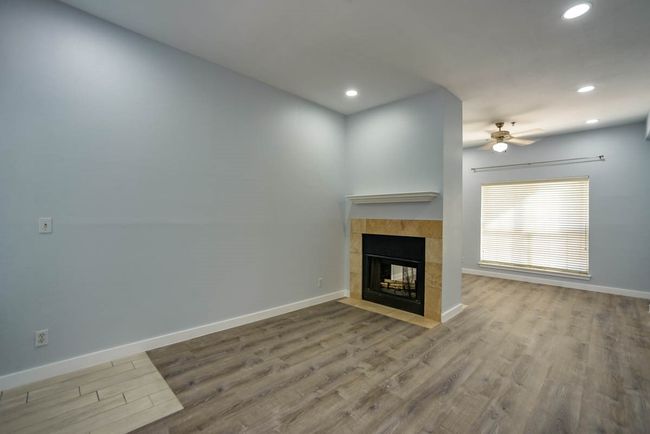 Unfurnished living room with a tiled fireplace, wood finished floors, a ceiling fan, and recessed lighting | Image 7