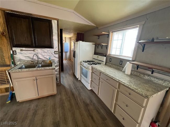 Kitchen featuring a sink, open shelves, dark wood-style floors, white gas range oven, and lofted ceiling | Image 7