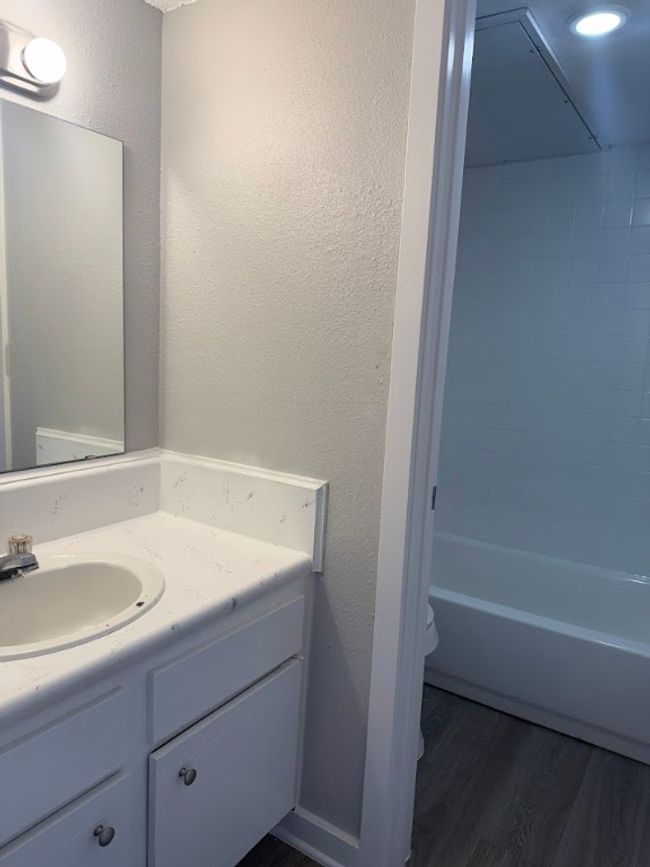 Bathroom featuring vanity, wood finished floors, a textured wall, toilet, and bathtub / shower combination | Image 11