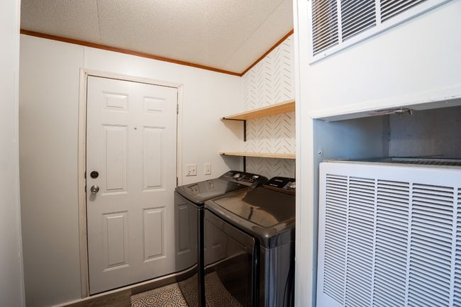 Washroom featuring a heating unit, washing machine and dryer, and crown molding | Image 30