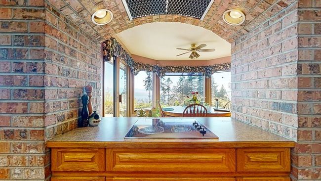 Kitchen with black electric cooktop, a wealth of natural light, and brick wall | Image 15