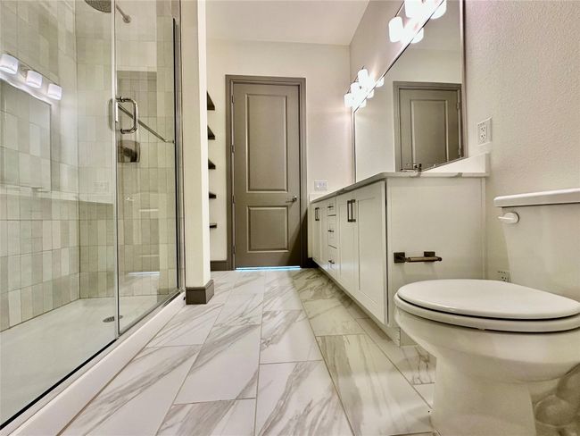 Bathroom featuring vanity, toilet, and a shower with door | Image 6