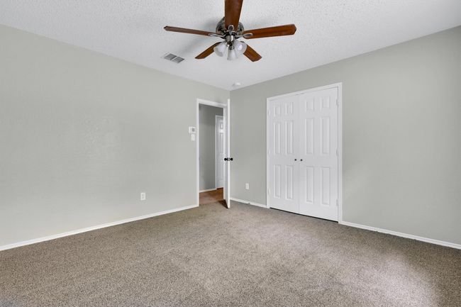 Unfurnished bedroom featuring a closet, carpet flooring, a textured ceiling, baseboards, and ceiling fan | Image 28
