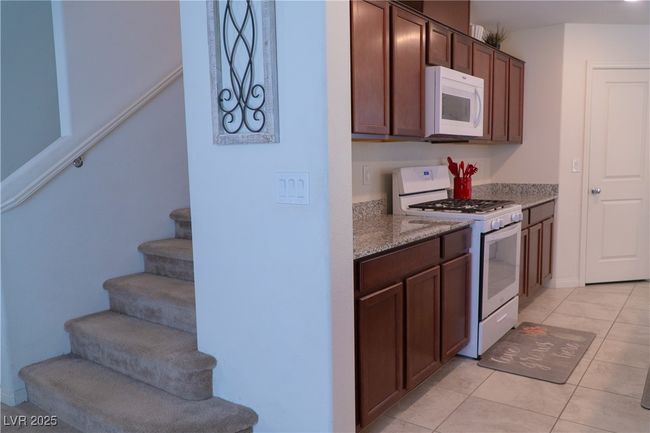 Kitchen with light stone countertops, light tile patterned floors, and white appliances | Image 21