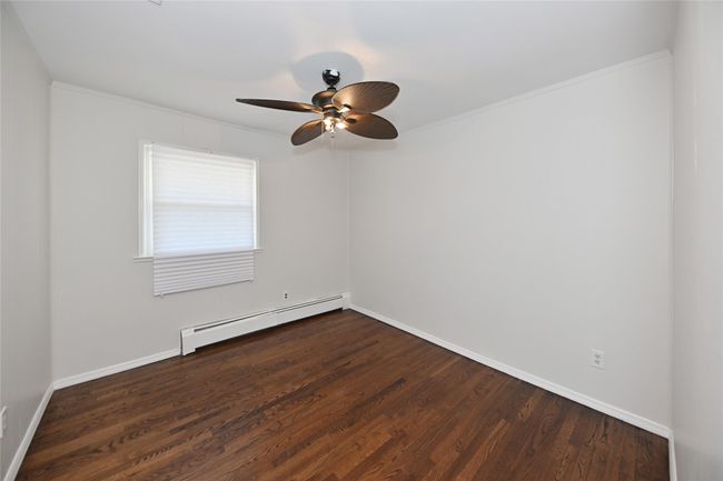 Empty room featuring a baseboard radiator, ceiling fan, dark wood-style floors, and baseboards | Image 20