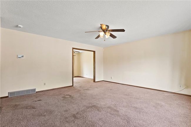 Spare room with a ceiling fan, light carpet, baseboards, a textured ceiling, and a smoke detector | Image 4