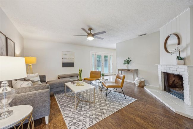 Living room with ceiling fan, wood finished floors, a textured ceiling, and a fireplace | Image 7