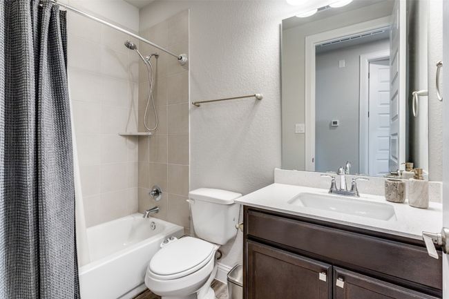 Bathroom with shower / tub combo, vanity, and a textured wall | Image 8