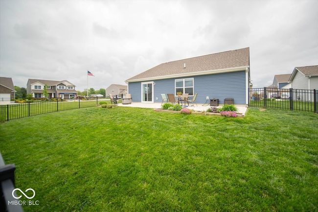 view of back of house from corner with a full concrete patio surrounded by black aluminum fence in the back yard. | Image 25