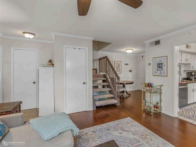 Living room with stairway, a ceiling fan, ornamental molding, and wood finished floors | Image 8