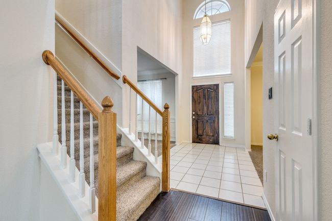 Foyer featuring baseboards, a high ceiling, wood finished floors, and stairway | Image 4