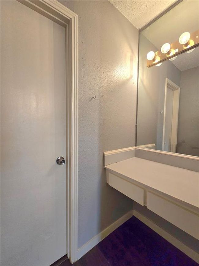 Experience a cozy vanity area featuring a large mirror, elegant overhead lighting, and a built-in countertop with convenient storage. Set against soft, light-colored walls, it's the perfect blend of style and functionality. | Image 10