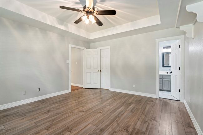Unfurnished room with a raised ceiling, a ceiling fan, dark wood-type flooring, and baseboards | Image 26