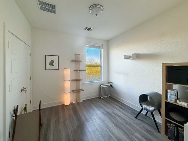 Second bedroom featuring visible vents, baseboards, and wood-look finished floors | Image 11