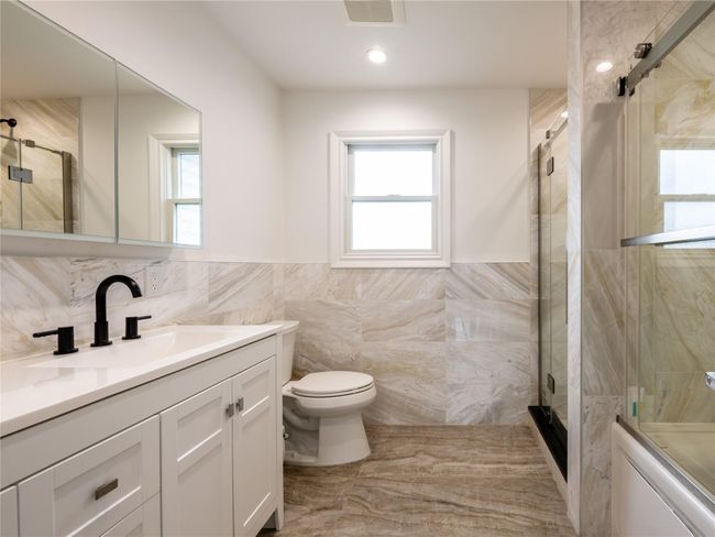 Full bath featuring tile walls, visible vents, an enclosed shower, and a healthy amount of sunlight | Image 22