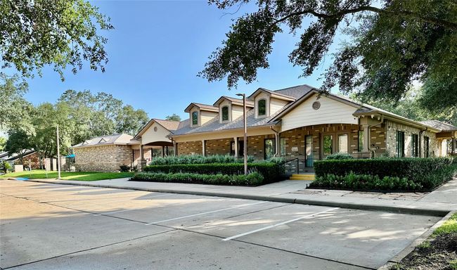 This photo shows a charming, single-story home with a stone and wood facade, surrounded by well-maintained landscaping. It features a shaded porch, gabled roof, and ample driveway space, set in a serene neighborhood with mature trees. | Image 15