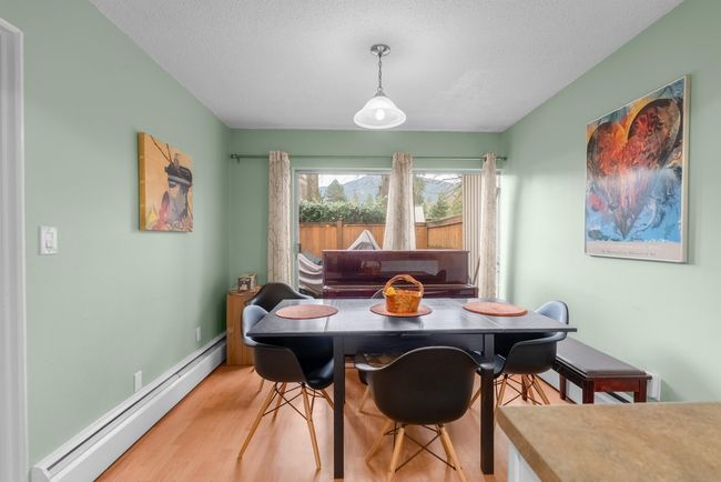 Dining area featuring a textured ceiling, wood finished floors, a baseboard heating unit, and baseboards | Image 6