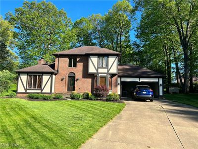 Tudor-style house featuring a garage and a front lawn | Image 1