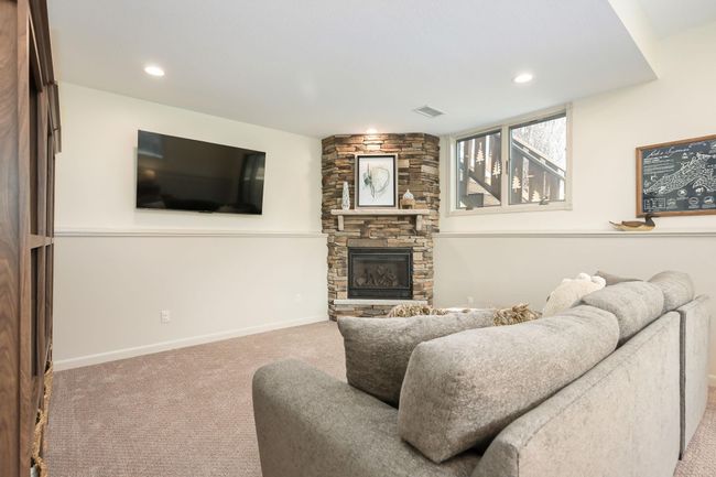 Lower level family room has corner fireplace with stone detail. | Image 4