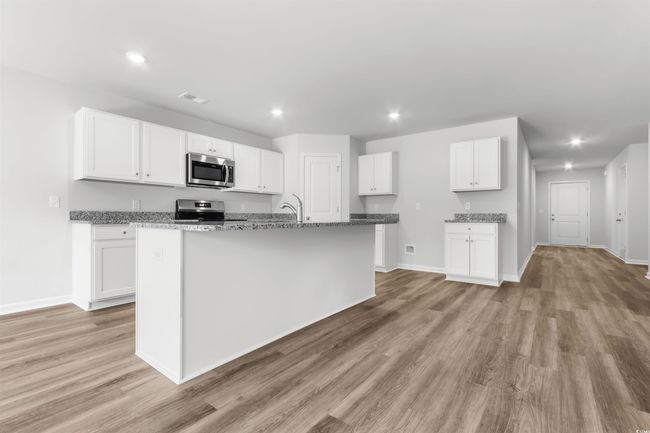 Kitchen with white cabinetry, stainless steel appliances, and a kitchen island with sink | Image 14