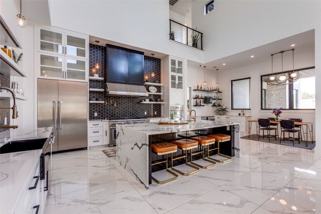 Kitchen with backsplash, a kitchen bar, open shelves, light stone countertops, and high quality appliances | Image 9