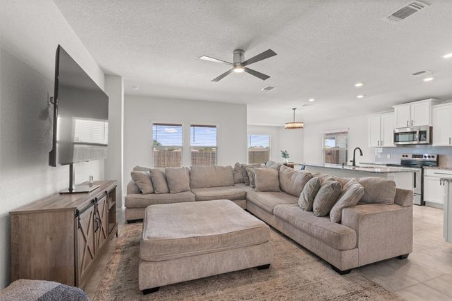 Living area with ceiling fan, a textured ceiling, recessed lighting, and open floor plan | Image 5