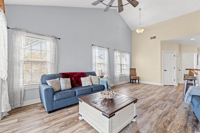 Living room with a wealth of natural light, visible vents, light wood-style floors, and a ceiling fan | Image 7