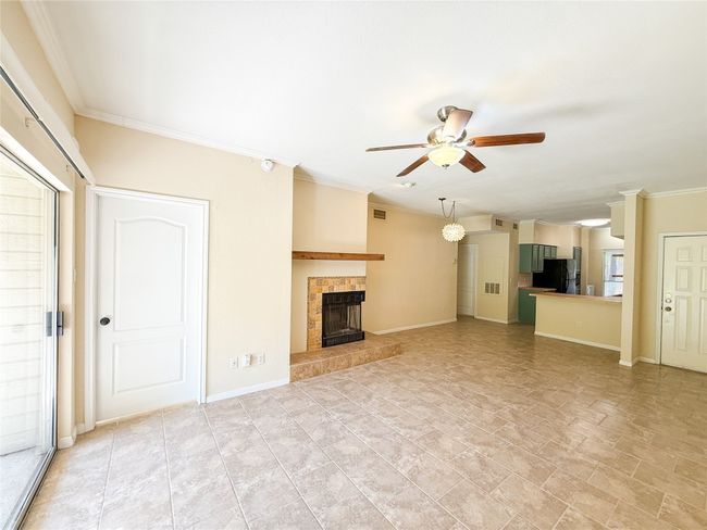 Unfurnished living room featuring crown molding, ceiling fan, and a fireplace | Image 10