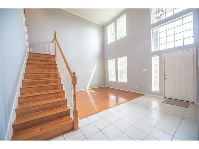 Foyer with stairs, light tile patterned flooring, a high ceiling, crown molding, and baseboards | Image 7