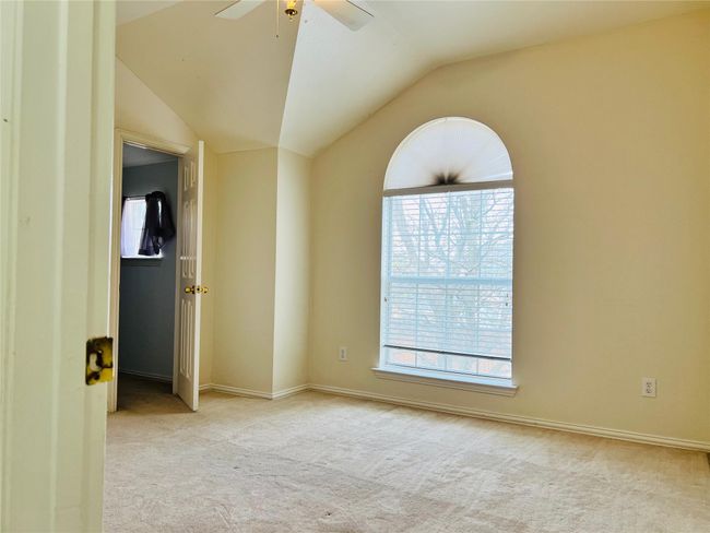 Empty room with ceiling fan, vaulted ceiling, and light carpet | Image 18