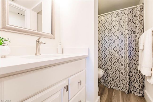 Bathroom featuring toilet, vanity, wood finished floors, and curtained shower | Image 17