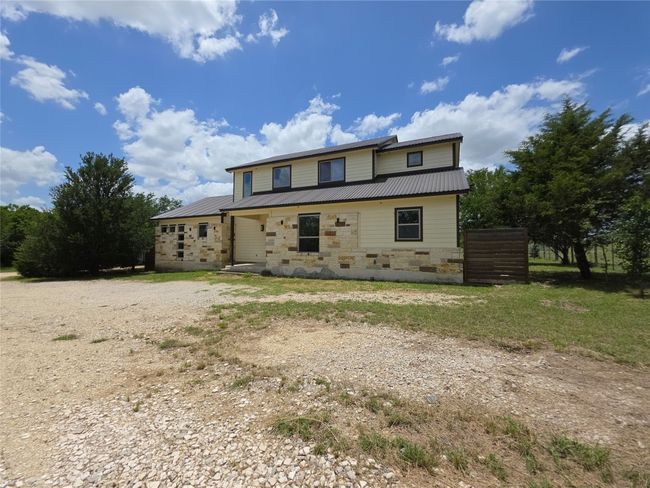 View of front of house with metal roof, stone siding, and dirt driveway | Image 28