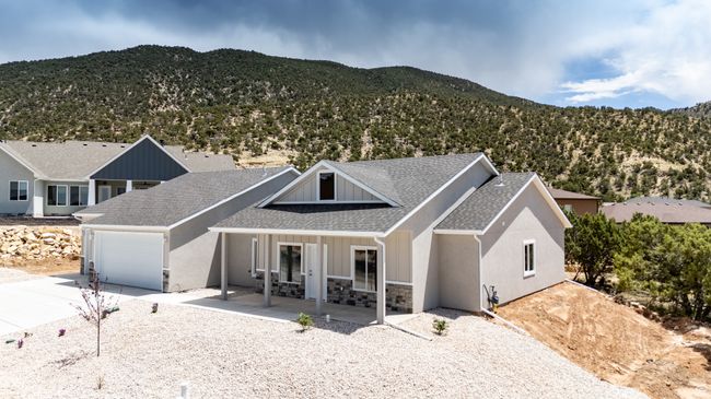 View of front facade featuring driveway, a mountain view, a shingled roof, an attached garage, and stone siding | Image 54