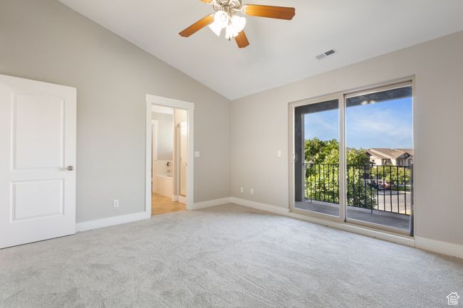 Unfurnished bedroom featuring access to exterior, light colored carpet, vaulted ceiling, connected bathroom, and a ceiling fan | Image 10