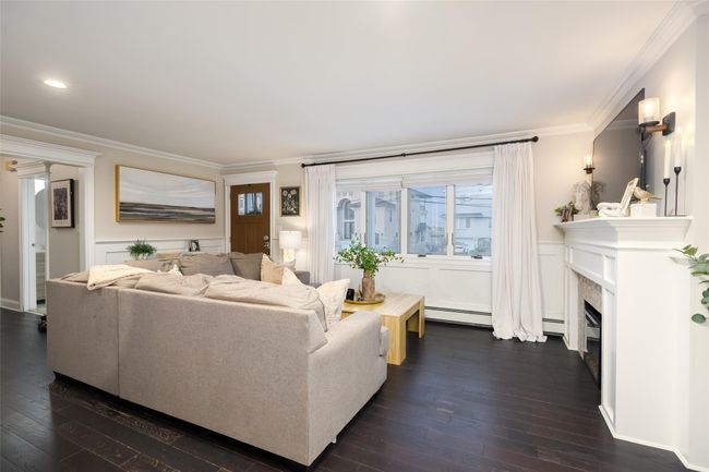 Living area with a baseboard radiator, crown molding, and dark wood-style floors | Image 14