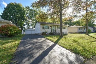 Ranch-style house with a front lawn, an outdoor structure, and a garage | Image 1