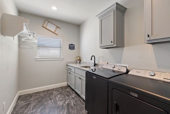Clothes washing area featuring baseboards, washer and dryer, a sink, and cabinet space | Image 27