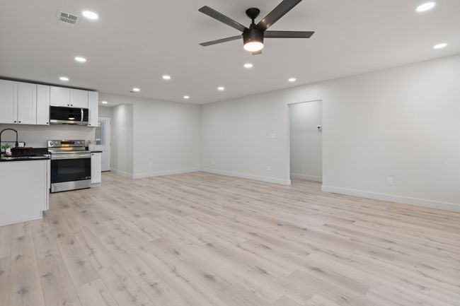 Unfurnished living room with a sink, light wood finished floors, ceiling fan, recessed lighting, and baseboards | Image 5