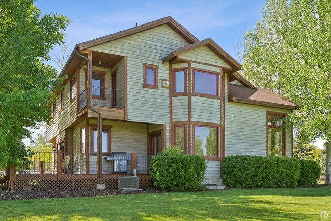 Rear view of property with a balcony, central AC unit, and a lawn | Image 64