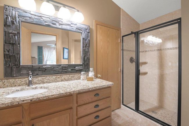 Owner's Bathroom with walk-in shower with tile surround, comfort height vanity with granite countertops, linen closet with additional doorway access from hallway, Anthropologie vanity mirror, with travertine flooring. Walk-in closet with built-ins! | Image 10
